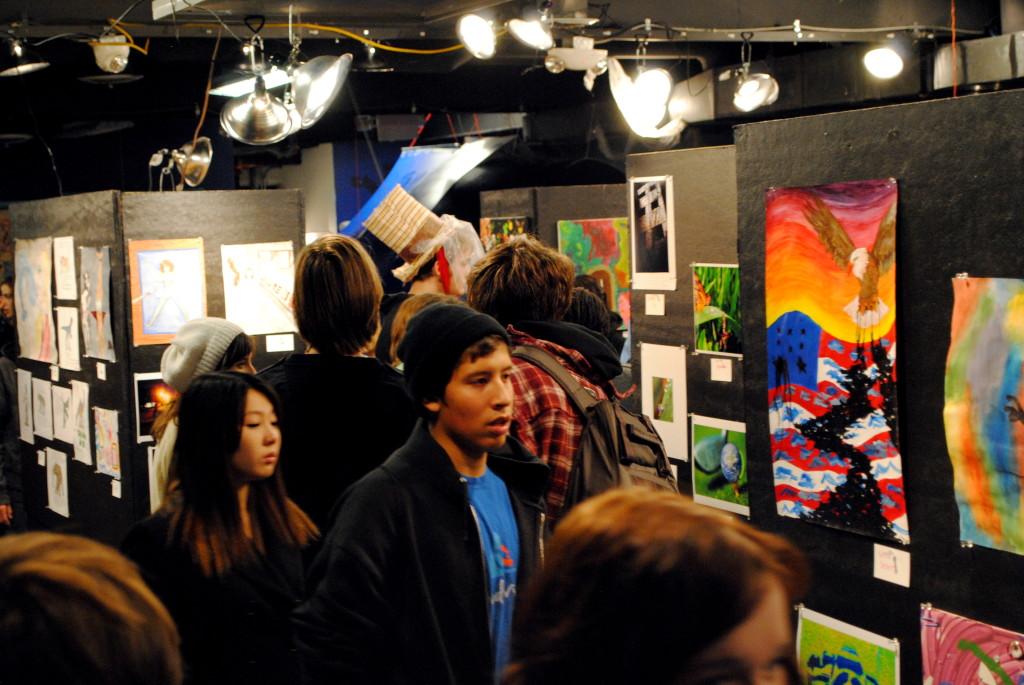 A crowd of teens looking at the art pieces.