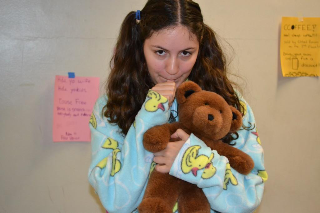 Julia Devarti, dressed as a baby, holds her teddy bear and sucks her thumb.