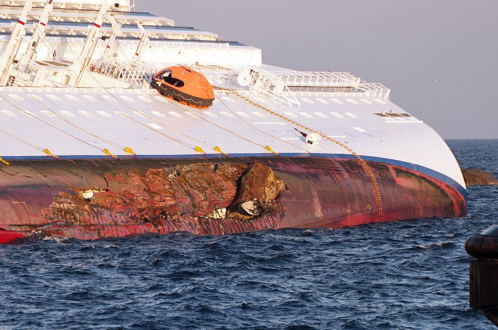 The Costa Concordia on her starboard side showing a rock embedded in the port side of her damaged hull. (wikipedia.com)