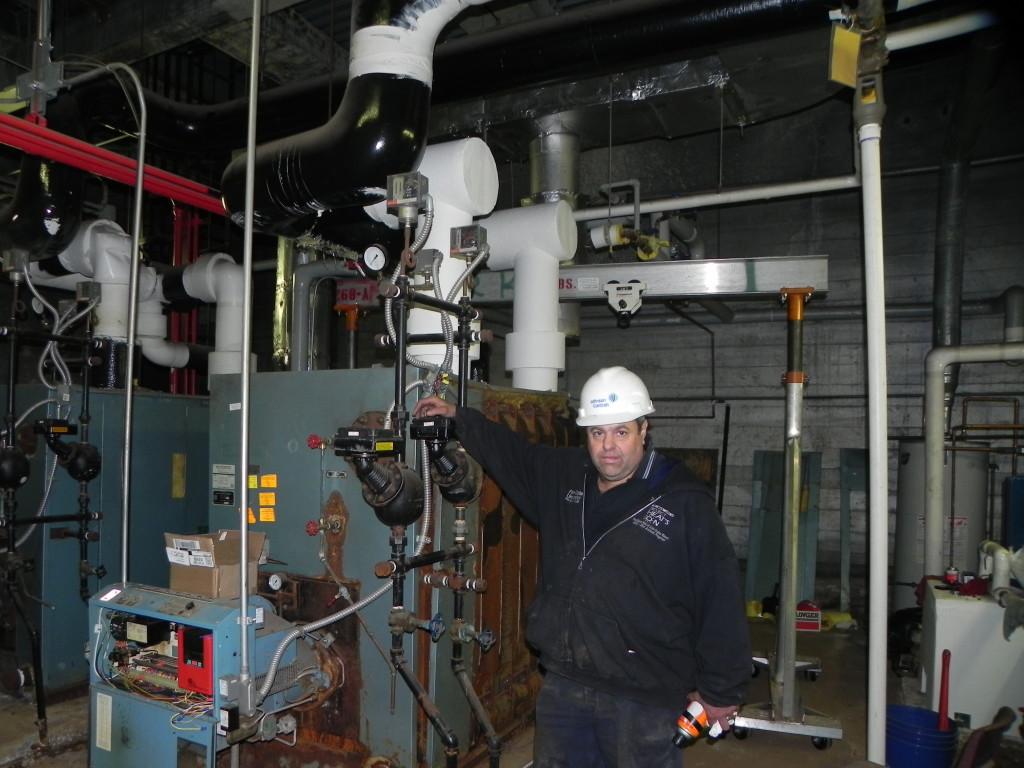 Andrew Bronson, employed by Johnson Controls, poses with one of the boilers.