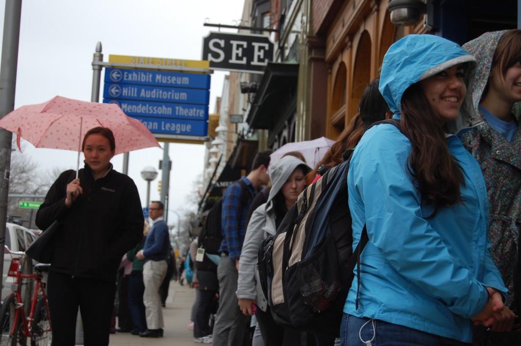 People wait cheerily in line even as a light drizzle falls.