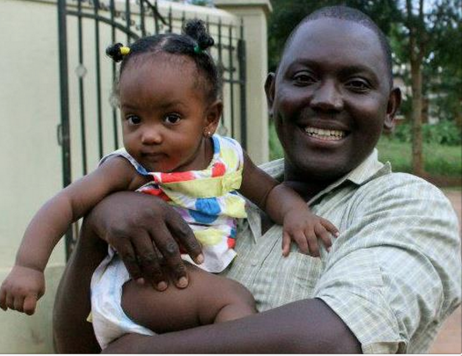 James Mutaka holds his 2-year-old daughter, Jessie, in front of their house in Uganda. 