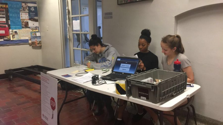 Julia Babaev, Cheyanne Anderson, and Morraina Tuzinsky look through the list of donors. The three volunteers text reminders and help blood donors check in.
