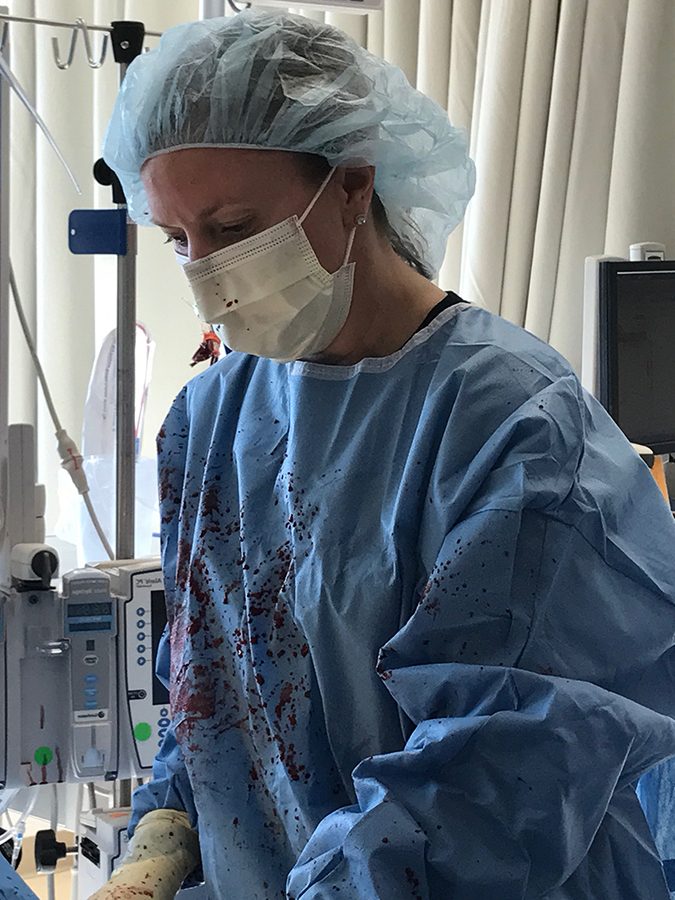 Romano gets a little messy as she saves a patient’s life. When she opened his chest, blood squirted up at her from his aorta, covering her surgical gown and mask.