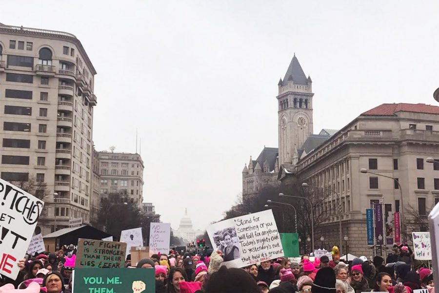 Thousands of women are pictured protesting in the third annual Womens March in front of the Capital Building. They held up homemade signs and were wearing pink hats  with ears like a cat. They were made as a jab-back at president Tump after stating he grab a women by the p***y. The word is also considered slang for a cat. 