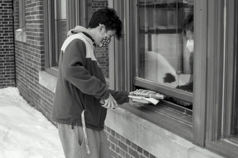 Nikolai Tang is handed his books from a southern window at CHS. Gretchen Eby, CHS secretary, was on the other side of the window. “We still have a lot of books to check out, but most of the students came and got the books that they needed,” Davis said.
