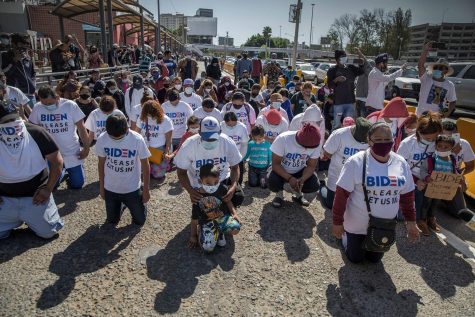 A group of migrants wearing T-shirts that read, Biden, please let us in, kneel and pray at the border crossing on March 2, 2021 in San Ysidro, Mexico. The group gathered and marched up to the border post to petition the new U.S. administration for asylum. U.S. Border Patrol (CPB) agents conducted a heavier operation at the border crossing with the goal of preventing a stampede. (Stringer/dpa via ZUMA Press/TNS)