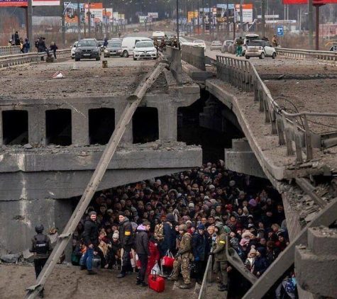 A crowd takes shelter under a bridge, looking over their shoulders with solemn expressions. Since Feb. 24, 2022, Russian bombs have rained down on Ukraine, destroying homes and taking lives.