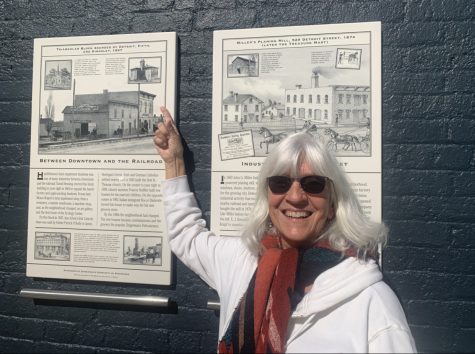 Cindy Haidu-Banks in front of a plaque featuring the Fourth Ward School.