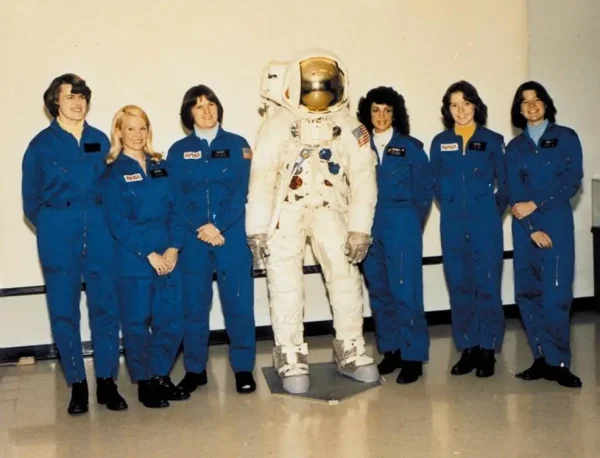 The six women astronauts selected by NASA in 1978, Shannon M. Lucid, left, M. Rhea Seddon, Kathryn D. Sullivan, Judith A. Resnik, Anna L. Fisher, and Sally K. Ride, pose with an Apollo-era space suit.