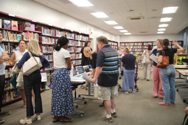 The Communicator's poster board sits on a table in the library. Journalists showcased all publications and handed out sponsorship forms, fliers advertising a fundraiser, and forms to buy a yearbook.