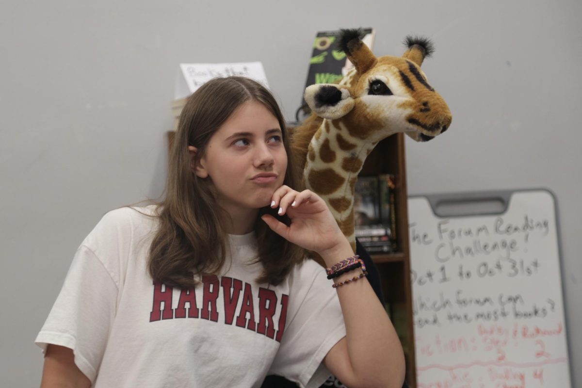 Addie McCready poses with Stella the Giraffe in front of the forum reading challenge bookcase. McCready had not been participating in the challenge, but held confidence in her forum to pull through.
“I personally am not doing the hottest on the reading challenge. I have not contributed a single book, but in my heart, I'm contributing,” McCready said. “I don't know how my forum is doing, but I know that we have some big readers, so hopefully they can pull my weight.”