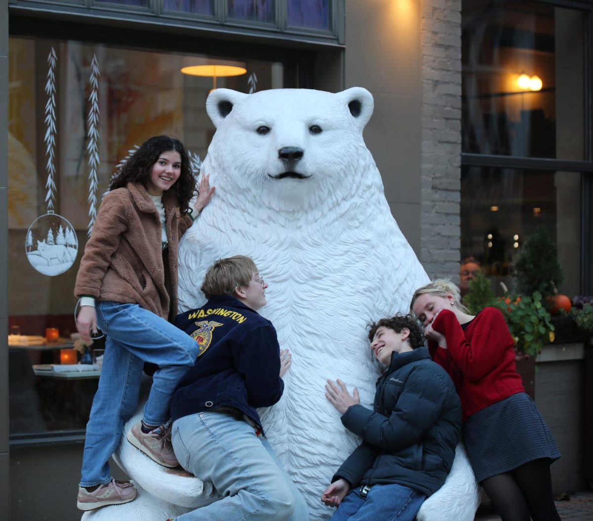 Toula Greenawalt (top left), Gwen Galvin (bottom left), Malcolm London (bottom right) and Claire Lewis (far right) huddle around the bear statue next to Sava's restaurant downtown. 