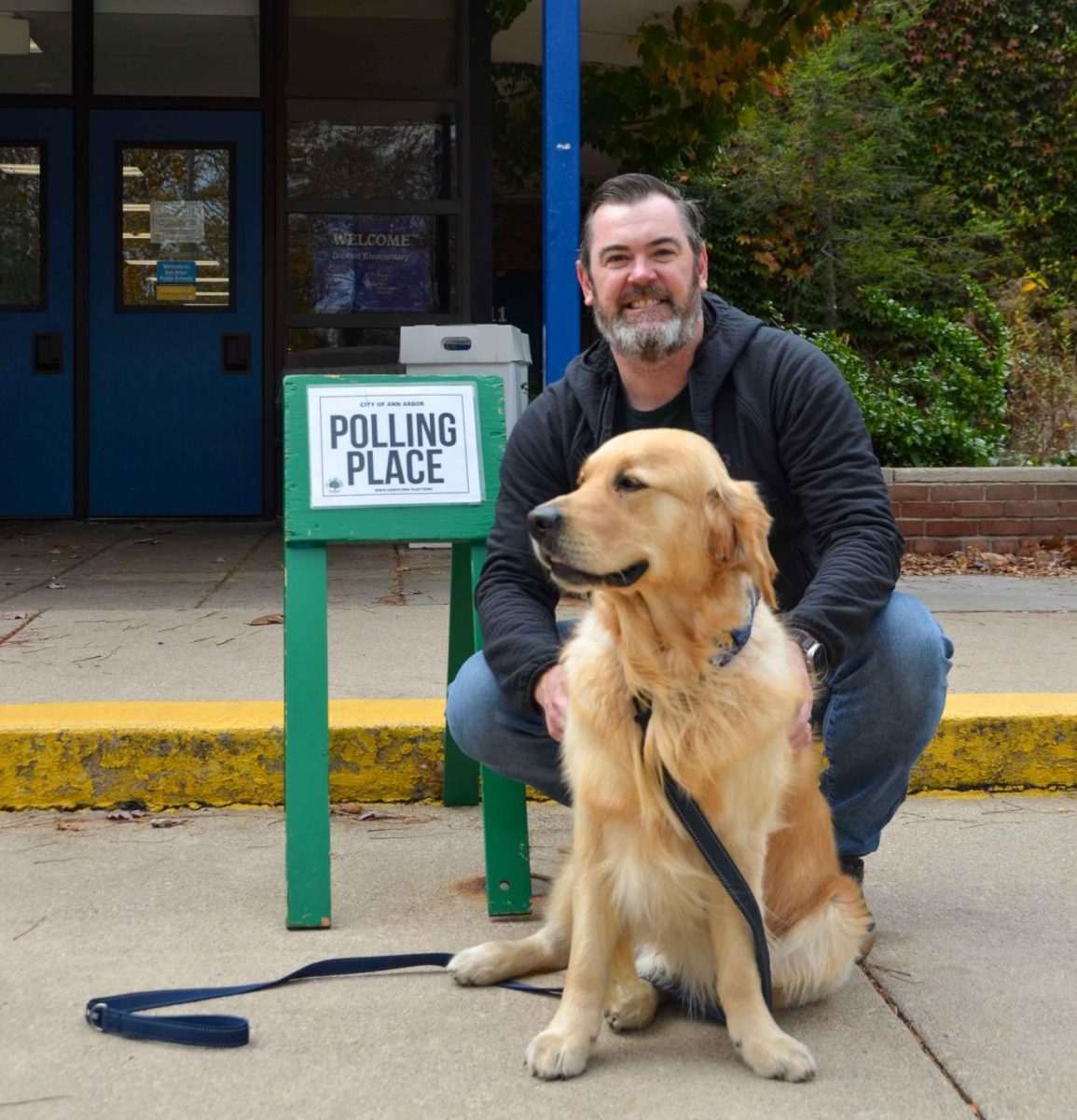 A man waits for his daughter at Dicken Elementary with his dog. He had already voted, but was her first time voting, so he wanted to be there to support her.