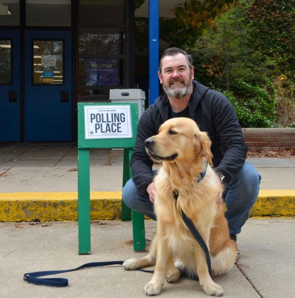 A man waits for his daughter at Dicken Elementary with his dog. He had already voted, but was her first time voting, so he wanted to be there to support her.