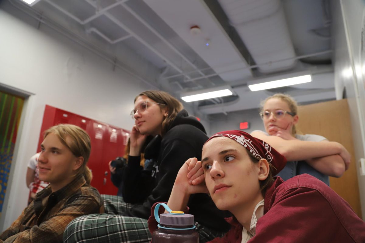 CET cast members Mathias Takacs (left), Maggie Williams (back right), and Luca Hinesman (front right) observe a local drag queen as she demonstrates her get-ready process for performing. 