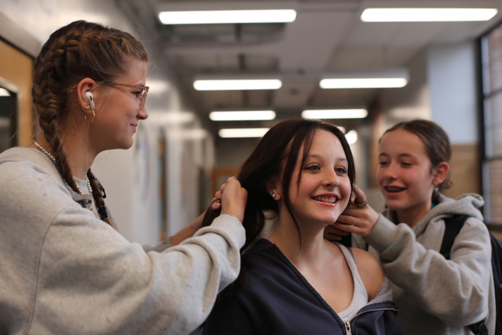 Alice Vandervliet, Eva Edwards, and Sadie Jacobs are braiding Edwards's hair after school in the hallway. Edwards thought that Vandervliet's French braids looked really good, so she wanted some herself. "We've all been super close since middle school, and Alice inspires me in many ways, especially with fashion and the way she looks," Edwards says. "I also think Sadie is artistic and her and Alice braiding my hair made me happy, knowing they are both so beautiful."