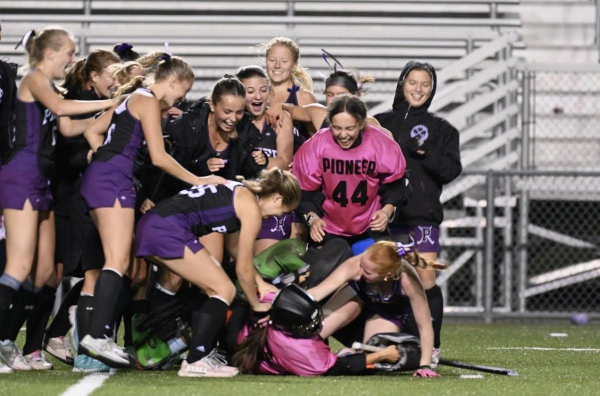 The Pioneer Field Hockey team jumps on top of Iseul Park after winning the state championship semifinals game