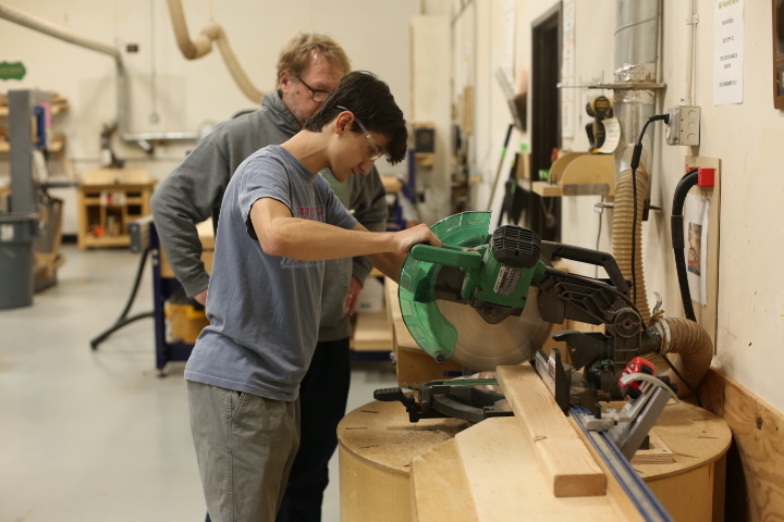 Dominic Nazario uses a miter saw to cut a 2x4 for use as a motor mount on a robot. The board was a bit of a rush job, with competition in less than a week, but making precise cuts was still important. "This saw is great because of how easy it is to line up the blade," Nazario said. "I'm very happy with how the piece turned out."