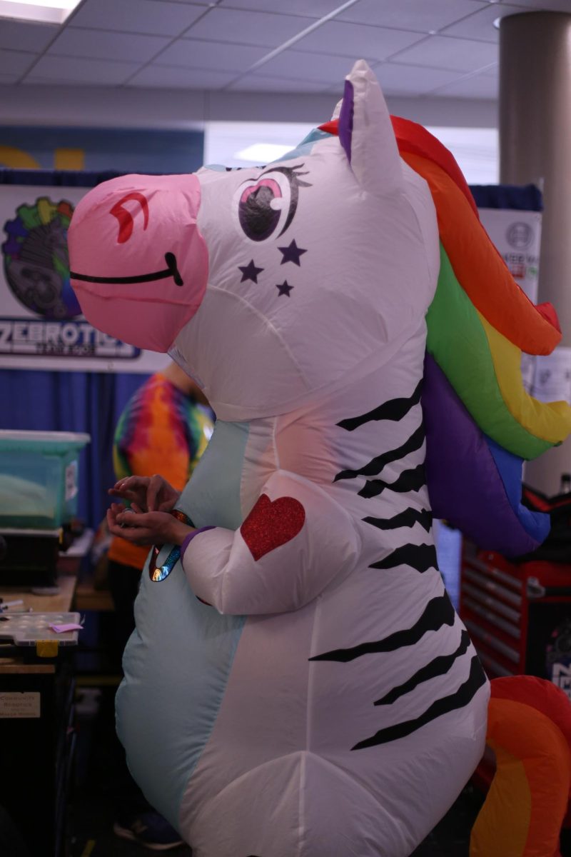 Charlie Guyton stands in the Zebrotics team mascot costume during a robotics competition. Although Guyton was not a member of the drive team, he found a way to show his support by wearing the costume. "I felt that we had to have someone exemplifying the Zebrotics spirit, and it had to be me," Guyton said. "It was great to put it on and really feel like part of the team."