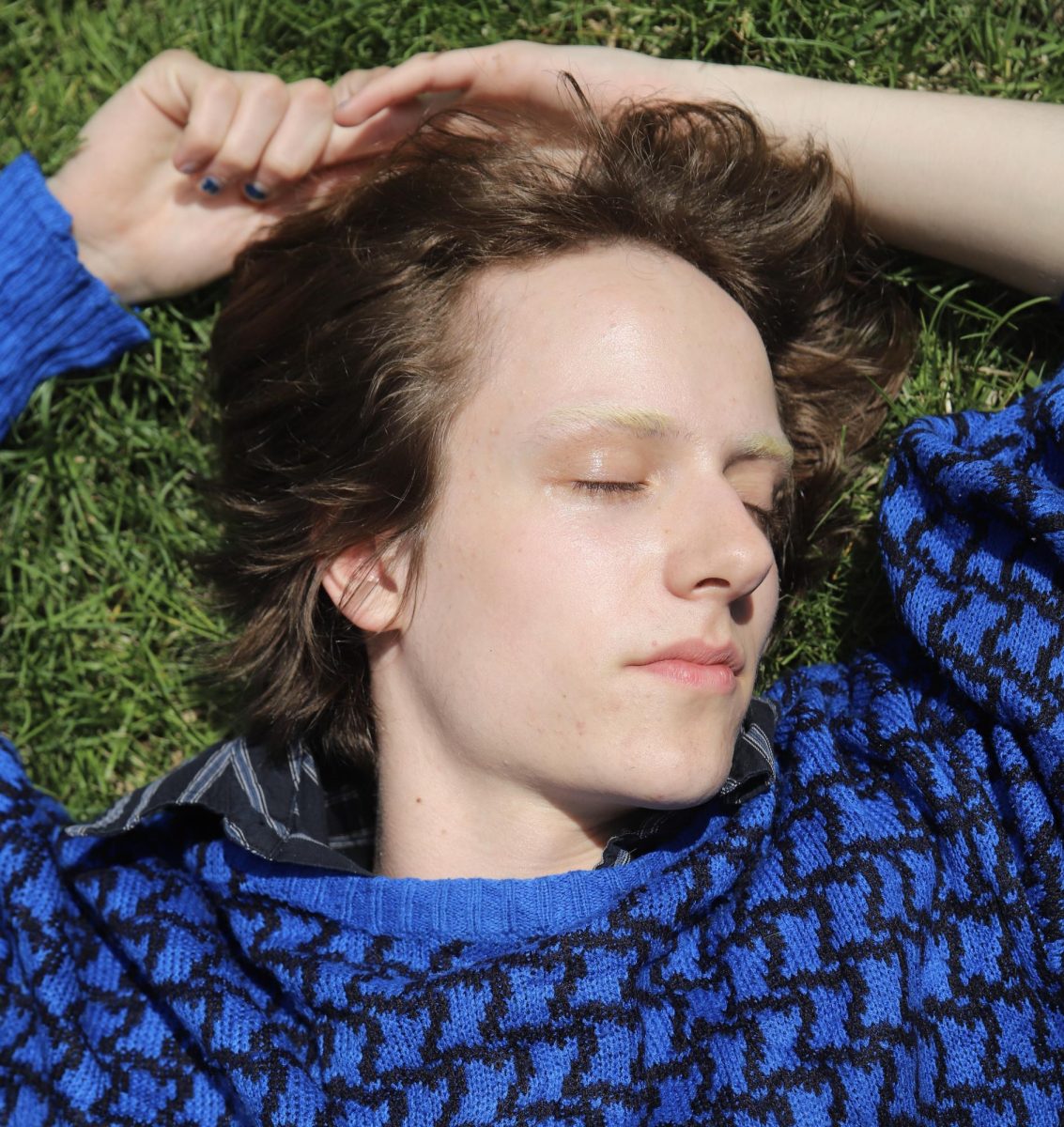 Luca LaVeta lies on the grass as the shine hits their face. 