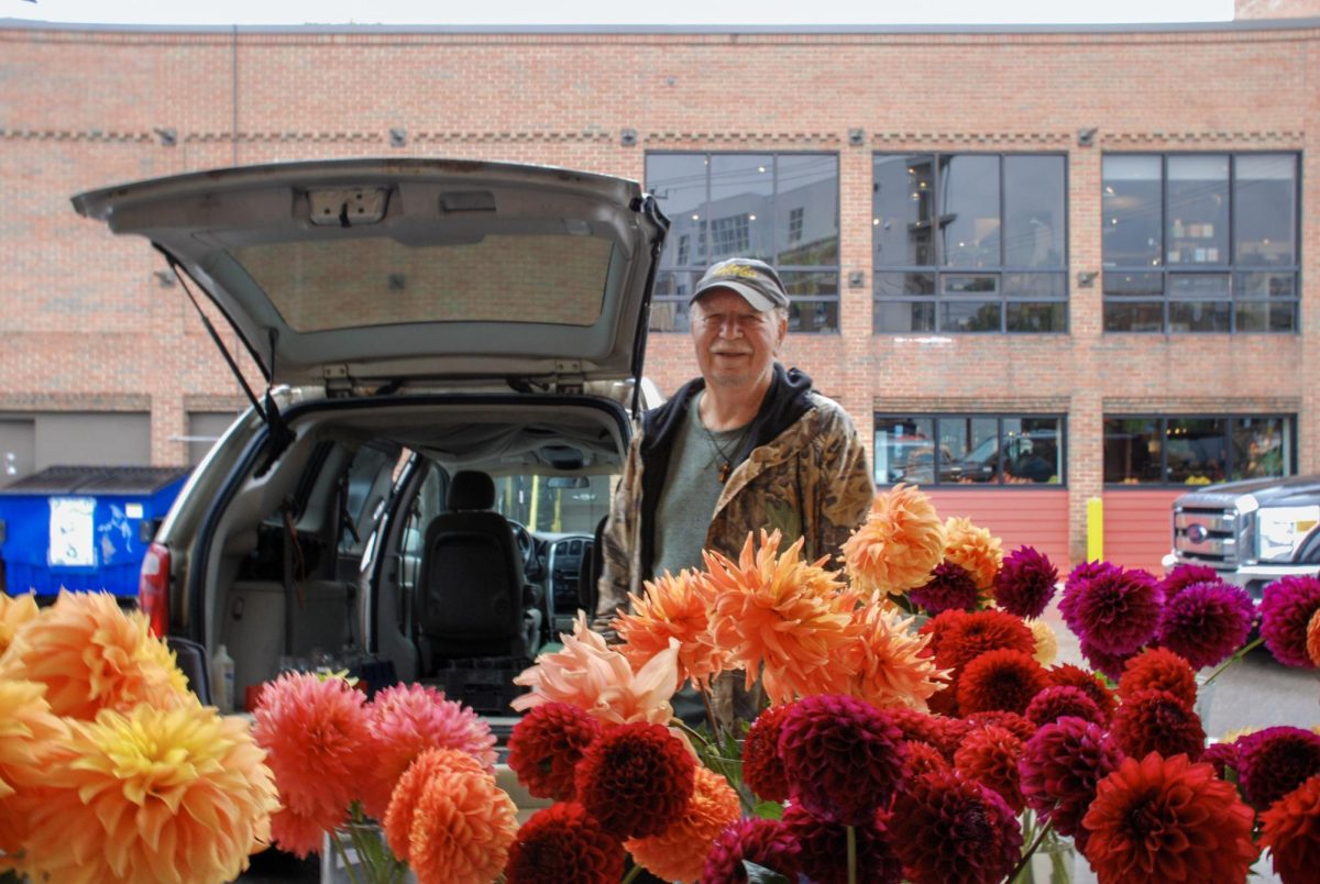 Tom Rumple stands among his variety of Dahlias for sale at the Kerrytown Farmers Market. Rumple was initially inspired to grow flowers by seed packet illustrations at the grocery store, but found much more benefit in the craft after joining a Dahlia society. "