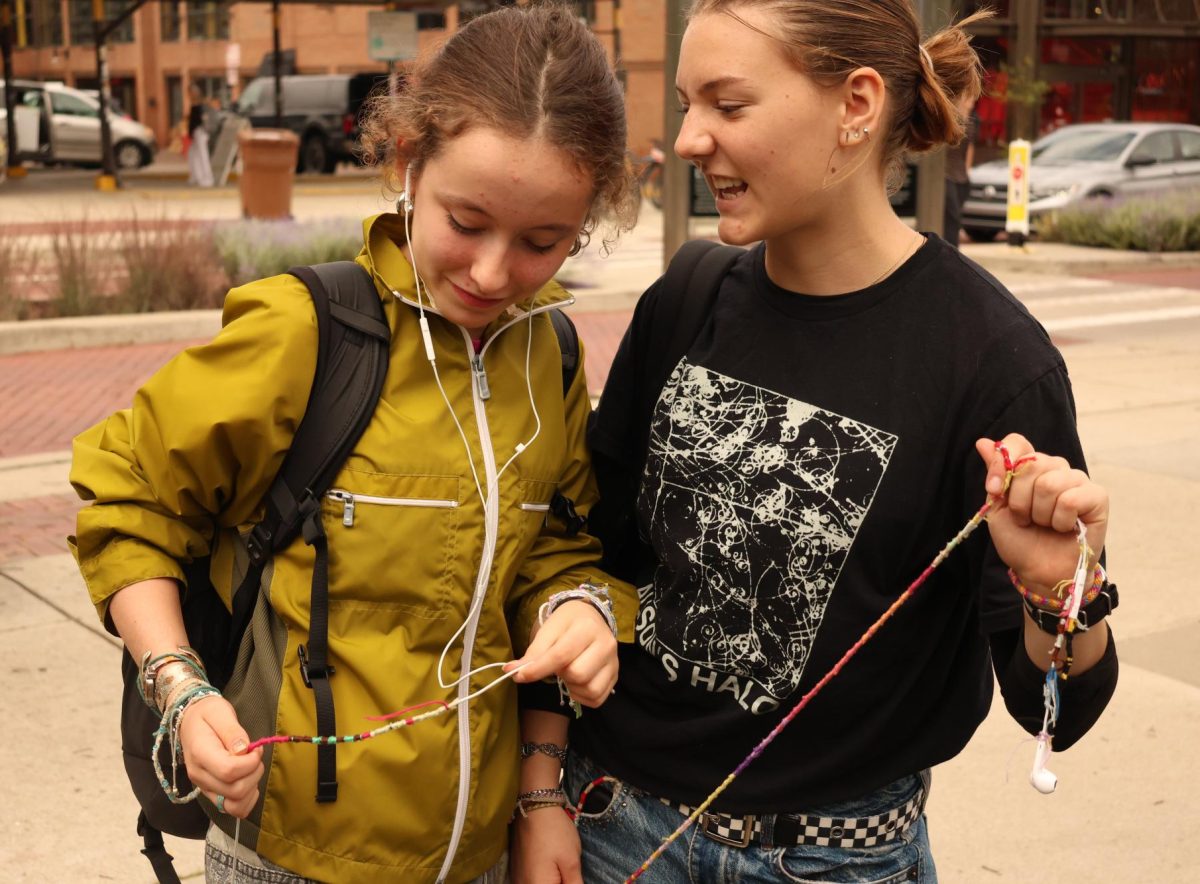 Sadie Jacobson and Ani Ledbetter compare their decorated earbud strings on the sidewalk near Kerrytown. Ledbetter had been sitting with some friends when Jacobson arrived, and the pair quickly realized that they were matching. "I just recently lost my earbuds, actually," Ledbetter said. "But then I found them, so it's all good."
