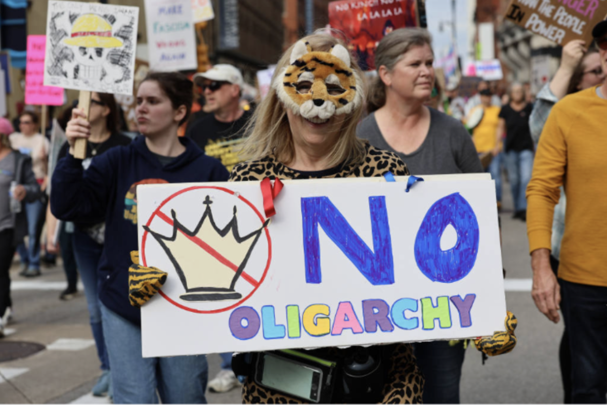 Carol Cummings holds her homemade "No Oligarchy" sign at the No Kings protest in Grand Rapids, Michigan. Two days before, Cummings dug through her costume bin to find the tiger costume she ended up wearing for her first ever protest. "Things have gotten to the point where it's a little worrisome as to how it'll ever be repaired," Cummings said. "I have seven grandchildren and I want a better world for them."