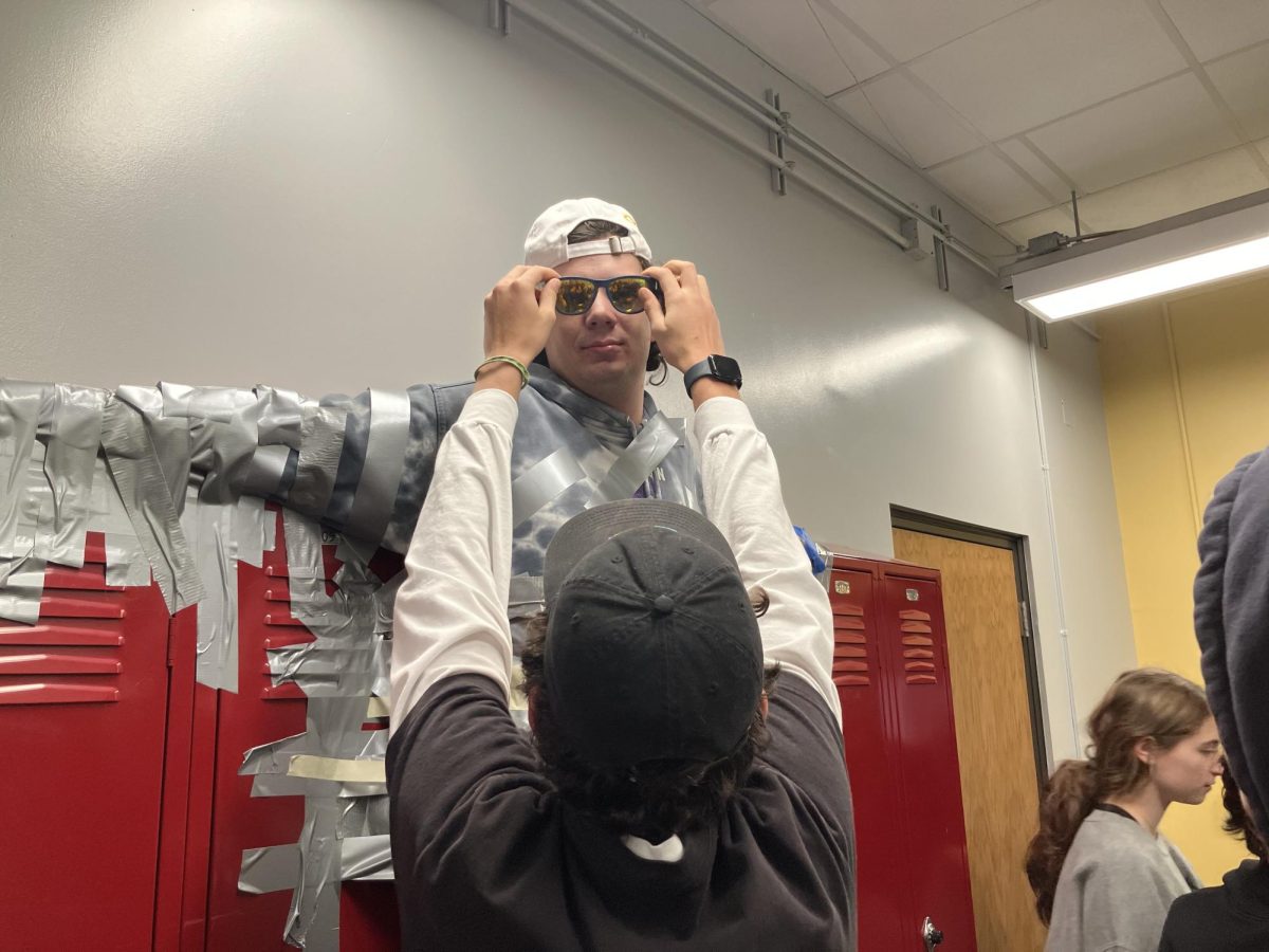 Alden Koschmann puts his sunglasses on Ryan Farr as he is taped to the wall. The Yager forum had hosted a fundraiser where students could pay to tape Farr to the wall outside room 311, and Koschmann didn't hesitate to add some spice to the event. "We decked him out in some sunglasses and a cross as well," Koschmann said. "It was a really fun way to end the week."
