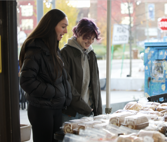 Jane Grocoff and Jesse Shtein contemplate buying cinnamon rolls at the Ann Arbor Farmer's Market. They were looking at the different baked goods the stand had to offer. "The cinnamon rolls looked really good," Grocoff said. "They are almost as big as Jesse's head."