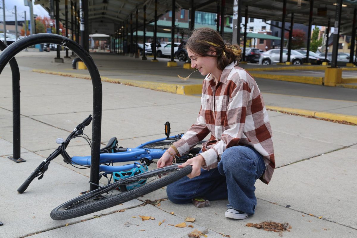 Sophomore Ingrid Kryscynski laughs as she realizes that someone has tried to disassemble and steal the front wheel off of her bike. Kryscynski was walking to Sweetwaters and realized that she should check on her bike that she had left outside of Kerrytown for over a week. "My mom is going to be so mad," Kryscynski laughed.