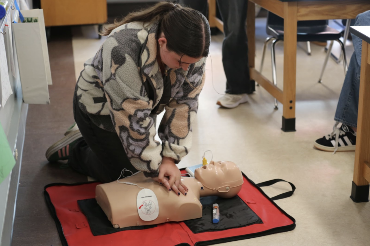 Junior Avery Nelson practices CPR on a dummy during a training class. 