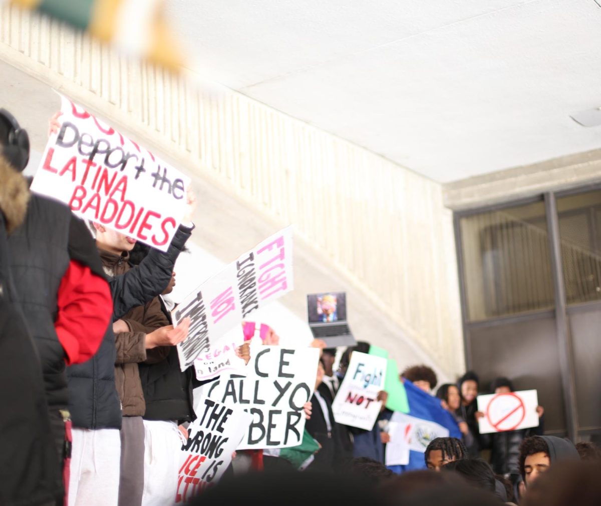 Huron students stand holding signs with messages against ICE.