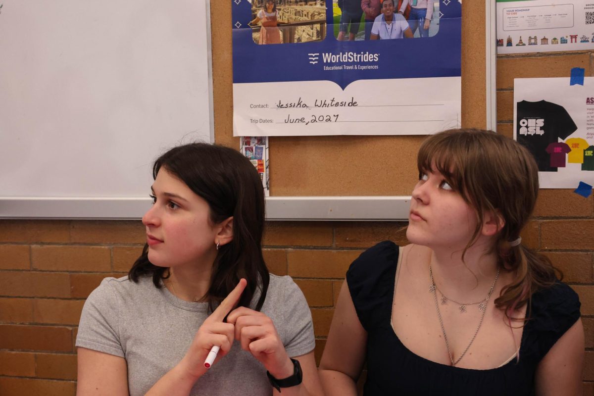 Rosie Matish and Willow Rosenfeld listen to Milly Sandstrom during Monday's walkout meeting. Matish and Rosenfeld had been making protest signs and writing letters to their senators. " I think it was really awesome for students to stay active in the community," Matish said. "When we all work together I think we can try and make real change, and I think that the fact that all of this, the letters and the walkout was all organized only by students is powerful."