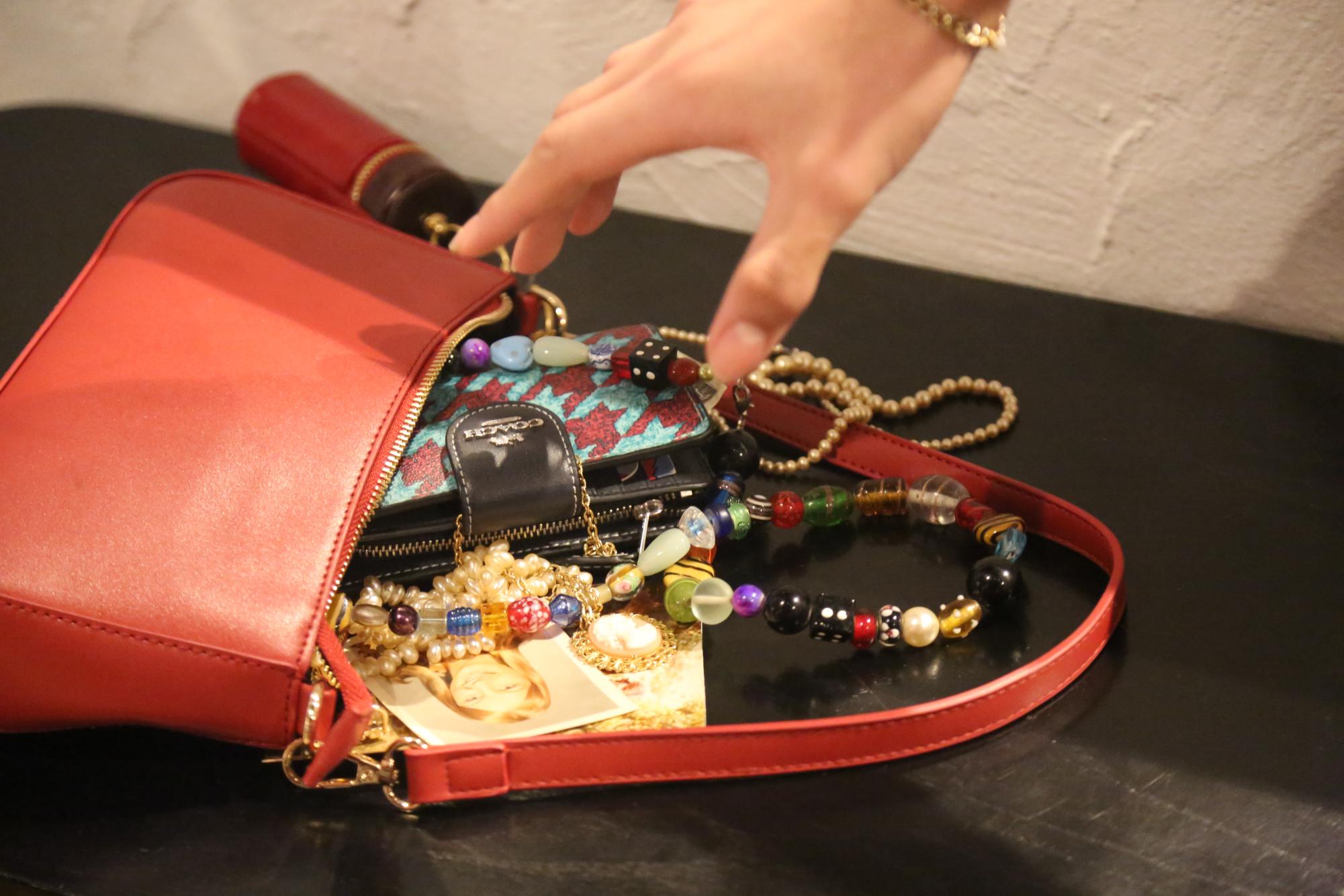 Rocky Zimmerman reaches for an item in a pile of random belongings. The contents of the purrse include everything from Zimermanns wallet to an array of jewlery. 
