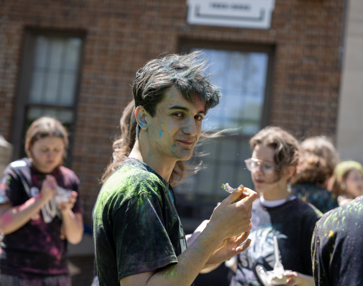 Dom Nazario eats ice cream in a CHS Zebra shirt covered in a rainbow of colored powder.